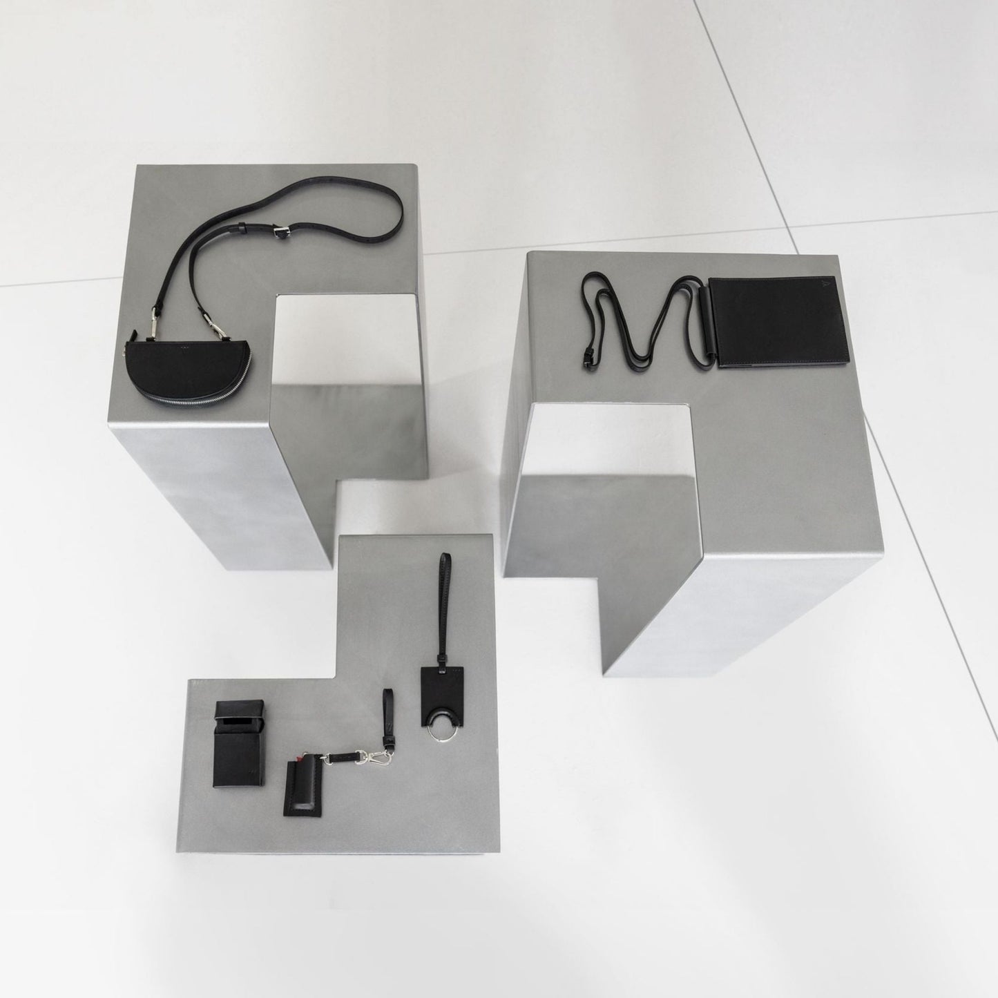 SIROKRIS aluminium display pedestals used as metal furniture platforms for black leather accessories.