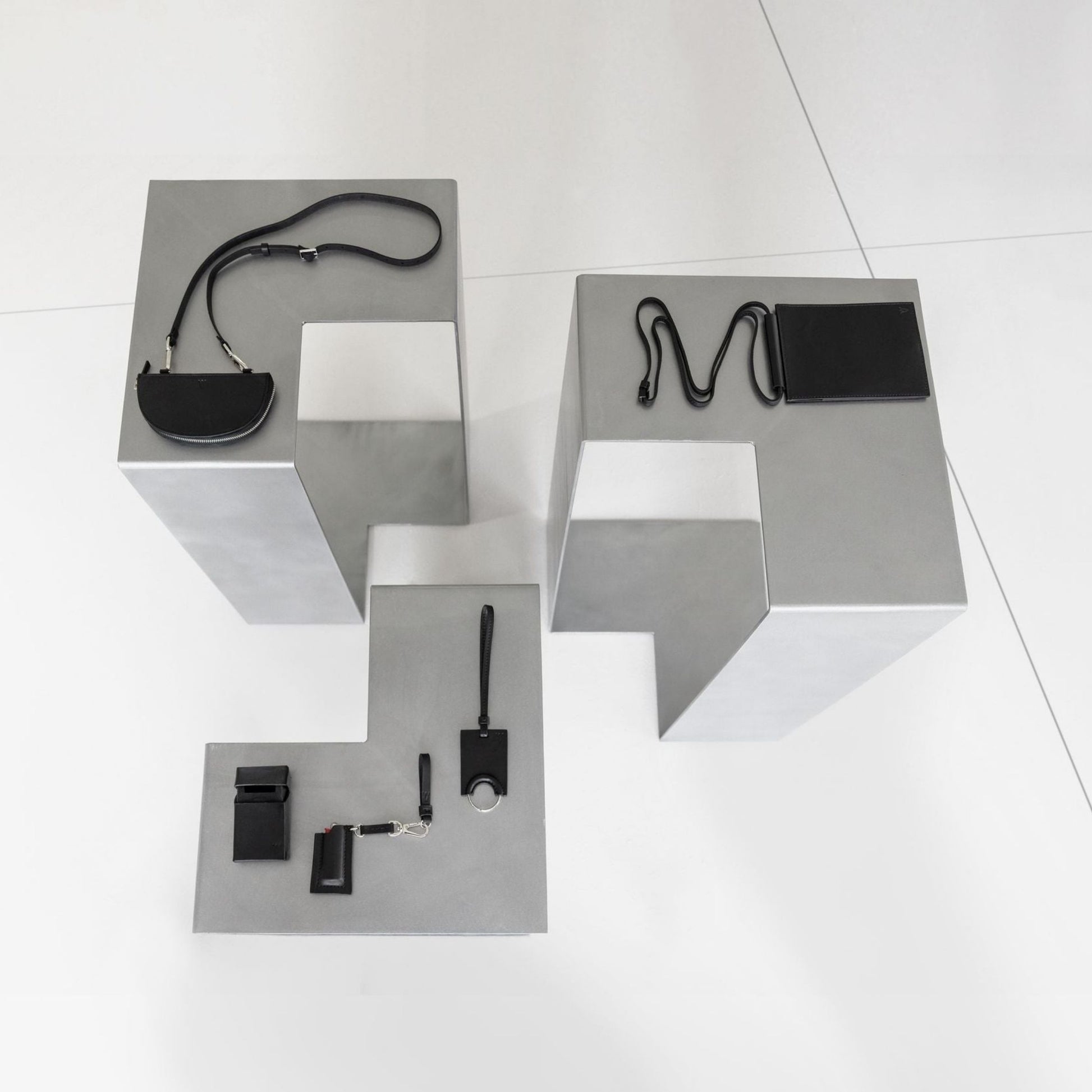SIROKRIS aluminium display pedestals used as metal furniture platforms for black leather accessories.