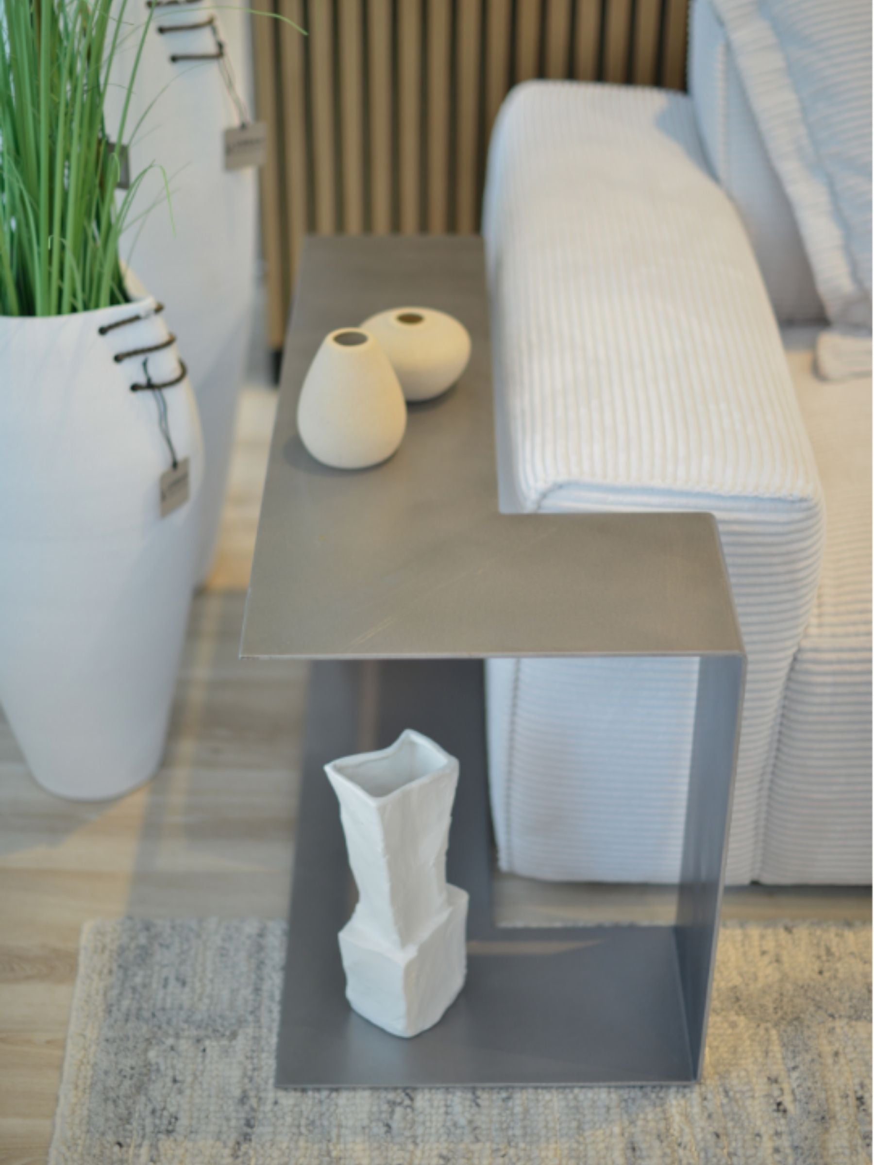 SIROKRIS Corner Sofa metal side table in steel next to a cream sofa.