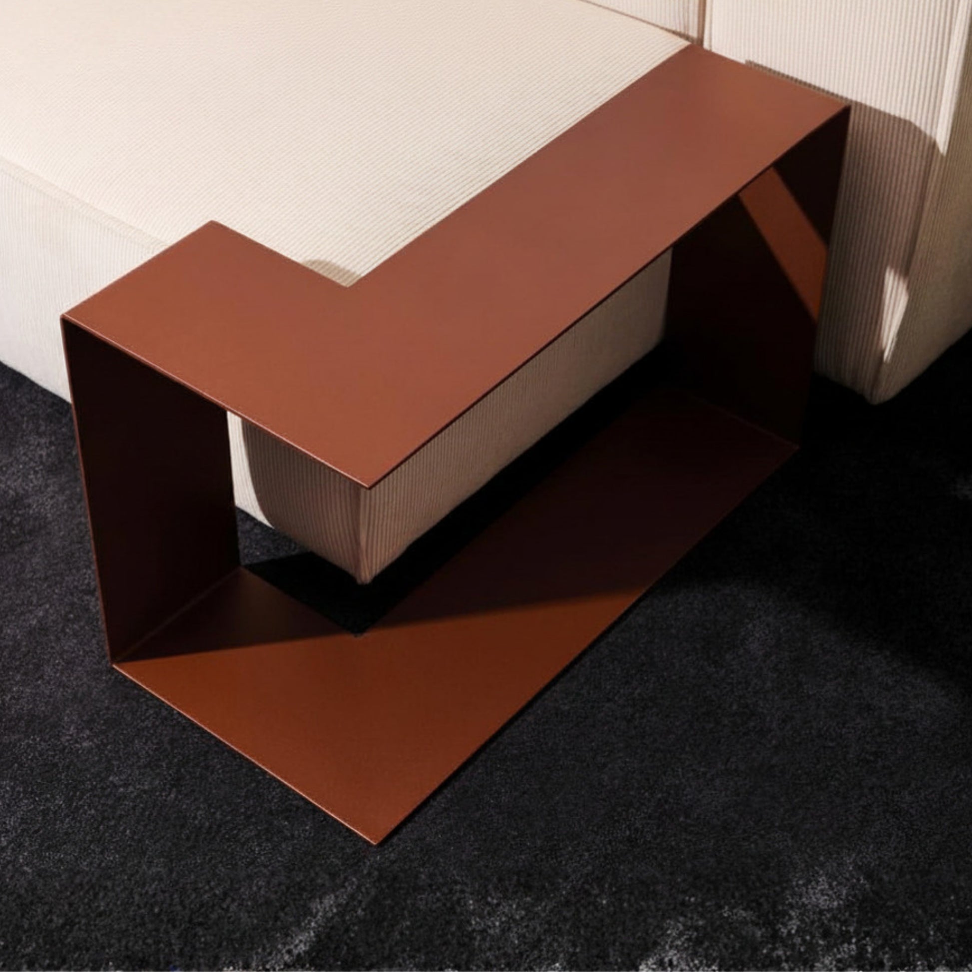 Bronzefarbener Beistelltisch aus Metall in L Form neben einem cremefarbenen Sofa