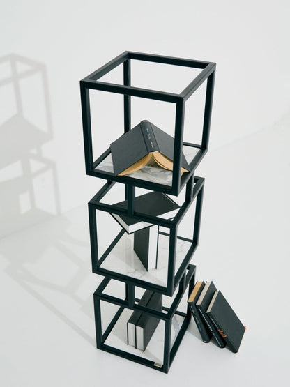 Modulares SIROKRIS Cube-Regal aus schwarzem Metall mit Marmorablagen, dekoriert mit Büchern auf weissem Hintergrund.